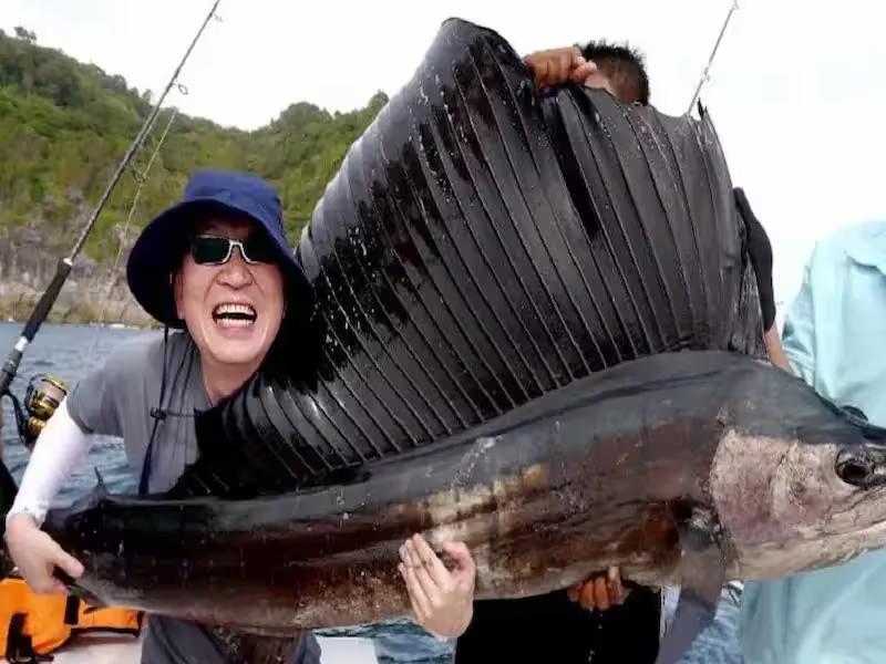 Happy fisherman displaying fresh tuna catch on deep sea fishing tour from Phuket