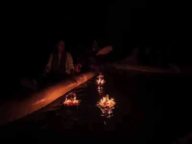 Magical moment of a floating Krathong illuminating bioluminescent plankton in a dark sea cave